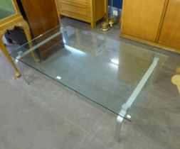 A LARGE OBLONG PLATE GLASS COFFEE TABLE, ON TWO BENT METAL END SUPPORTS, 4'7" X 2'8"