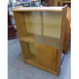 A LIGHT OAK BOOKCASE AND GLASS SLIDING DOORS AND CUPBOARD