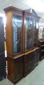 GEORGE III STYLE FIGURED MAHOGANY BREAKFRONT LIBRARY BOOKCASE, WITH BROKEN ARCH PEDIMENT, THREE