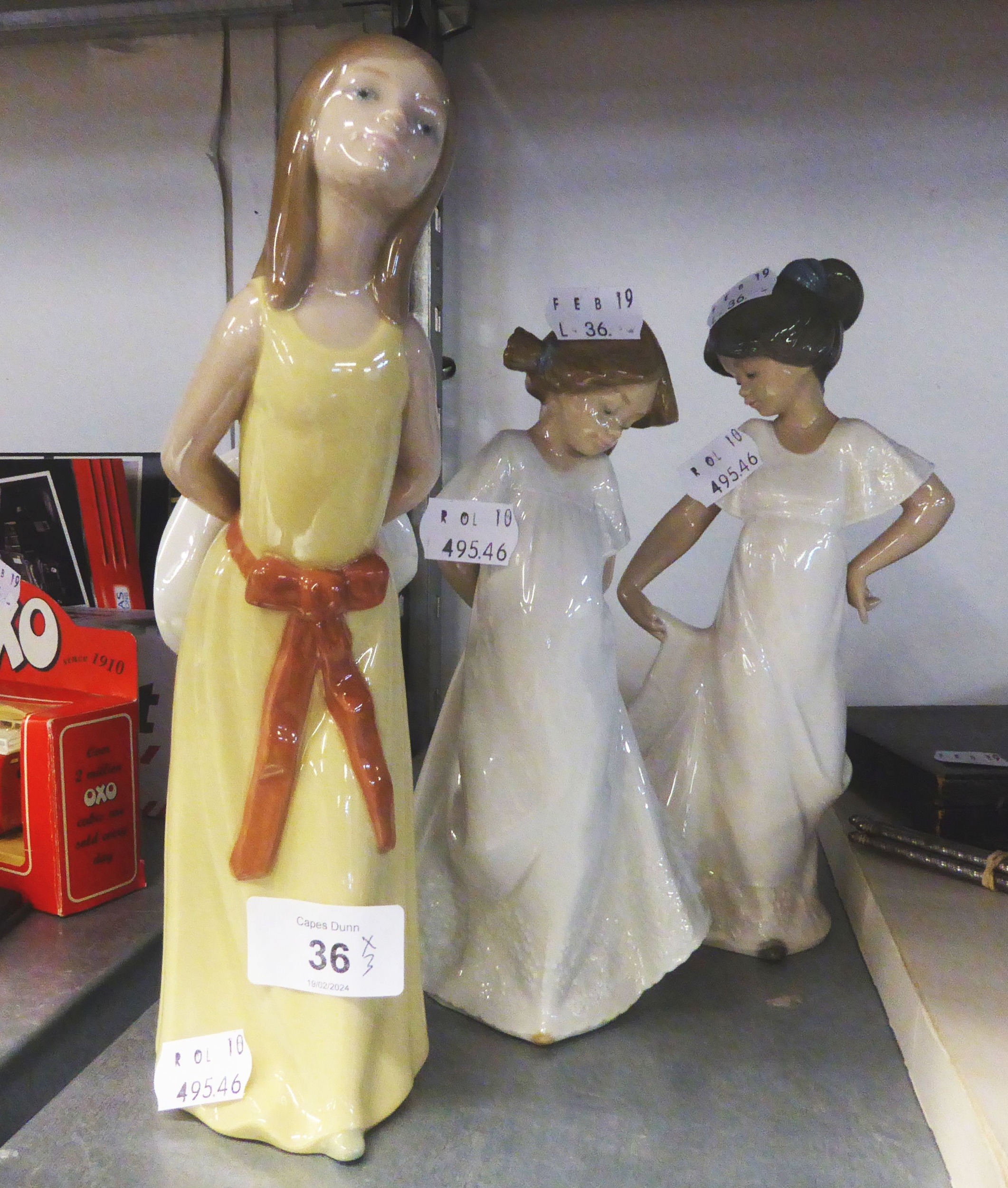 A LLADRO FIGURE OF A YOUNG GIRL HOLDING A HAT AND TWO NAO FIGURES OF GIRLS IN WHITE DRESSES (3)