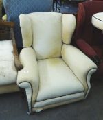 1930's OVERSTUFFED WING ARMCHAIR, IN CREAM UPHOLSTERY WITH BROWN PIPING, RAISED ON BUN FEET