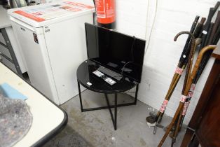 A SMALL FLAT SCREEN TELEVISION ON A CIRCULAR BLACK GLASS TOPPED TABLE