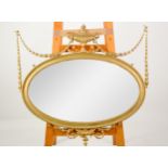 REGENCY STYLE WALL MIRROR: Modern gilt neo-classical oval wall mirror in the Regency style, with