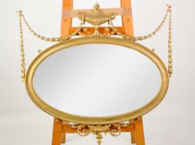 REGENCY STYLE WALL MIRROR: Modern gilt neo-classical oval wall mirror in the Regency style, with