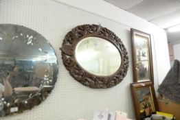 AN OVAL WALL MIRROR IN CARVED OAK FRAME, AND A SMALL OBLONG MIRROR IN SILVERED FRAME