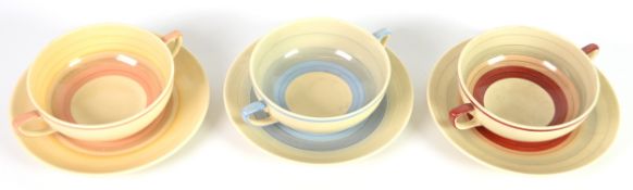 SET OF THREE SUSIE COOPER POTTERY CONSOMME CUPS AND SAUCERS, banded in colours, together with a