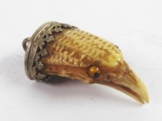 VICTORIAN CARVED BIRD CLAW PENDANT, carved as the head of a bird with tiny glass eyes, with