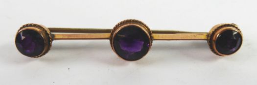 9ct GOLD RAZOR EDGE BAR BROOCH, collet set with three round amethysts, 1 3/4in (4.5cm) wide, 2.8gms