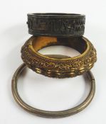 THREE MIDDLE EASTERN HINGE-OPENING BANGLES, viz an embossed gold plated broad bangle; an engine