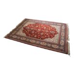 MACHINE WOVEN WOOL CARPET OF PERSIAN DESIGN, with all-over Herati design on a wine red field, with
