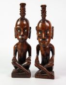 PAIR OF ETHNOGRAPHIC CARVED WOODEN FIGURES seated crossed legged, with bone inset eyes, 13 ½" (34.