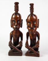 PAIR OF ETHNOGRAPHIC CARVED WOODEN FIGURES seated crossed legged, with bone inset eyes, 13 ½" (34.