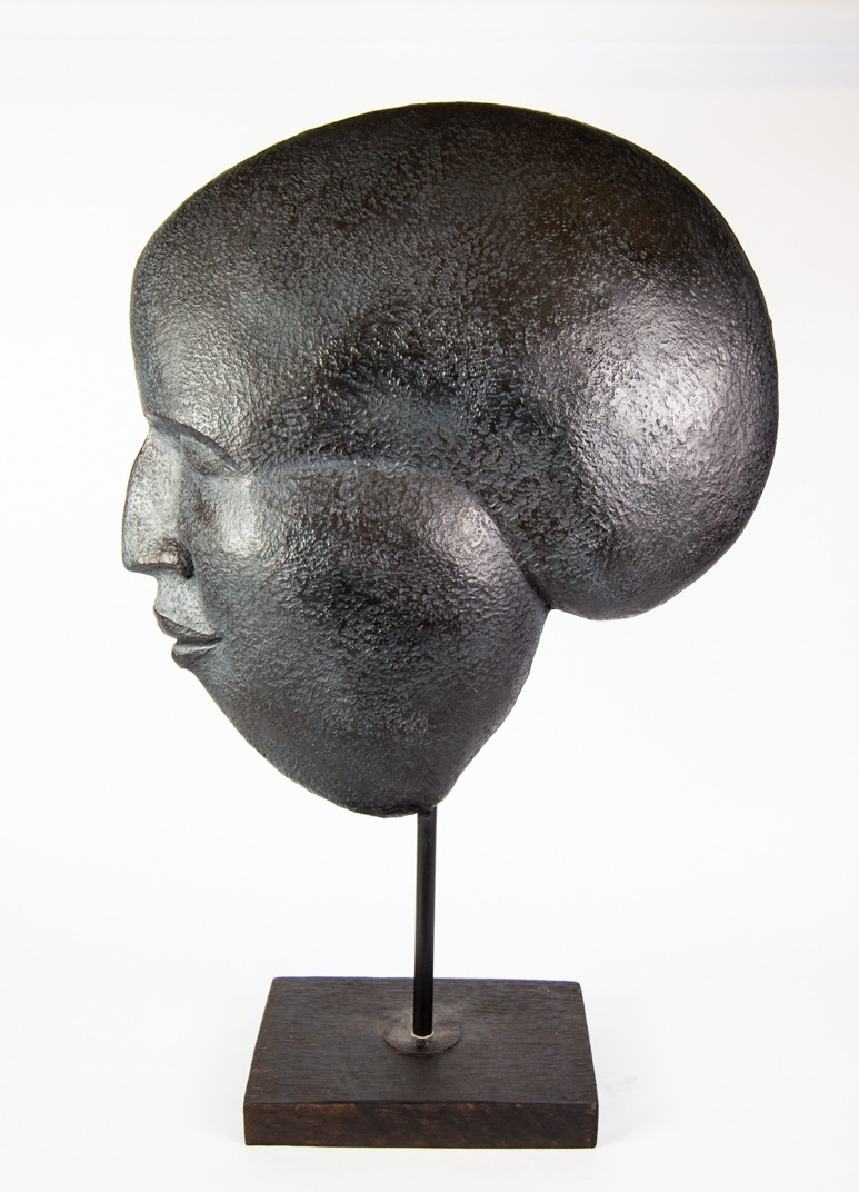 MODERN BLACK TEXTURED PLASTIC HEAD SCULPTURE, modelled in profile with black stained wood oblong