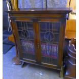 AN OAK BOOKCASE ENCLOSED BY TWO LEAD LIGHT DOORS, 3’3” WIDE