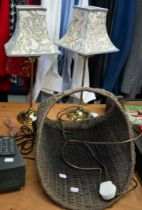 A SMALL WICKER LOG BASKET AND TWO BRASS EFFECT BEDROOM TABLE LAMPS (3)