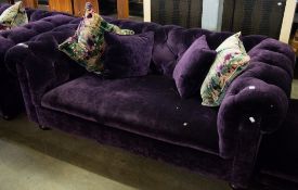 A STYLISH FULLY UPHOLSTERED PURPLE VELVET COVERED TWO SEATER CHESTERFIELD SETTEE, RAISED ON TURNED