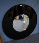 A LARGE CIRCULAR BLACK GLASS FRAMED MIRROR (102cm) DIAMETER