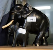 AN INDIAN CARVED EBONY ELEPHANT AND A SMALLER DITTO, (A.F.) (2)