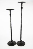 GRADUATED PAIR OF MODERN BLACK METAL FLOOR STANDING CANDLE HOLDERS, each with slender, knopped