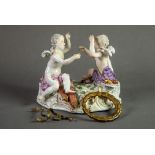 19th CENTURY MEISSEN PORCELAIN GROUP OF TWO CHERUBS, each seated on the rococo embossed white