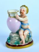 CONTINENTAL PORCELAIN FIGURE, painted in colours and gilt, and modelled as a seated cherub, sat on a