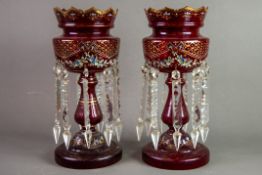 PAIR OF RUBY GLASS TABLE LUSTRES, each of typical form with wavy rims and prism cut glass drops,