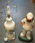 A COLD PAINTED LARGE DOORSTOP, IN THE FORM OF A CRICKETER AND A POTTERY URN SHAPED LAMP (2)