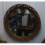 A CIRCULAR WALL MIRROR IN PIERCED GILT FRAME