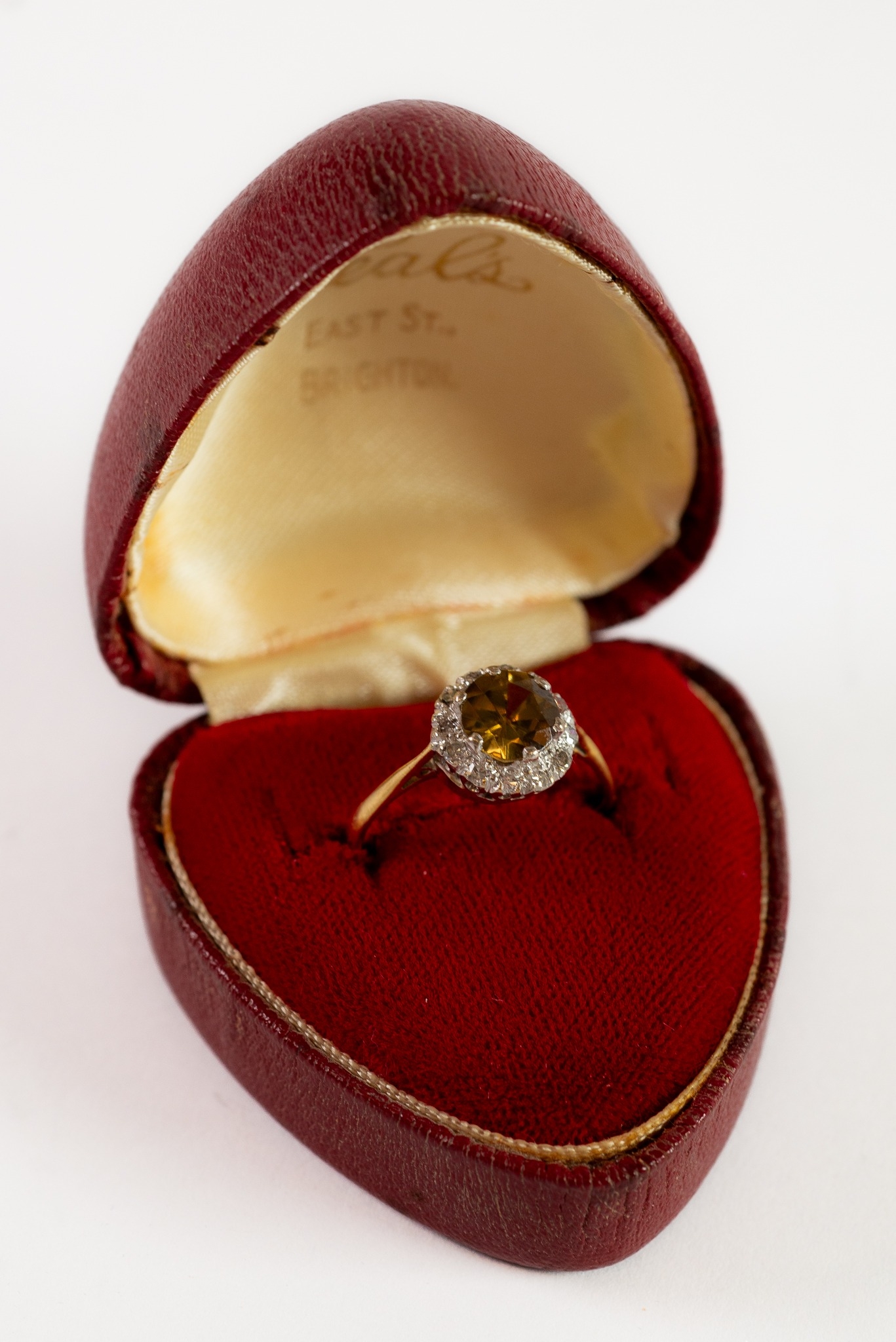 GOLD COLOUR METAL (no carat mark) YELLOW/GREEN STONE SET RING, within a border of TINY DIAMONDS, 2.8
