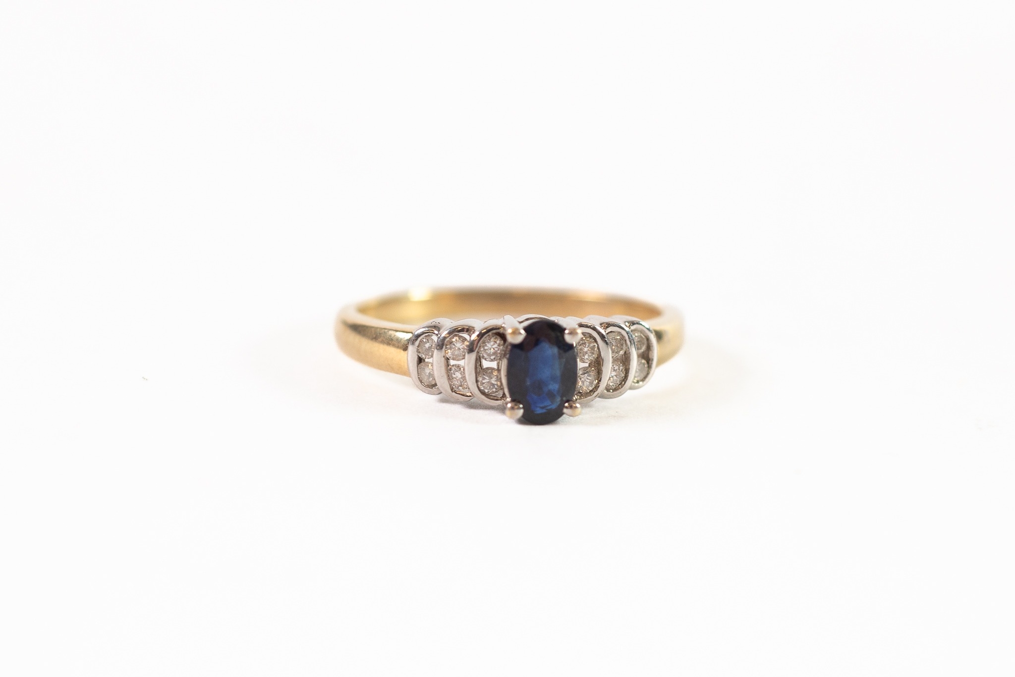 9ct GOLD SAPPHIRE AND DIAMOND RING, the oval sapphire claw set, six tiny diamonds set in stepped