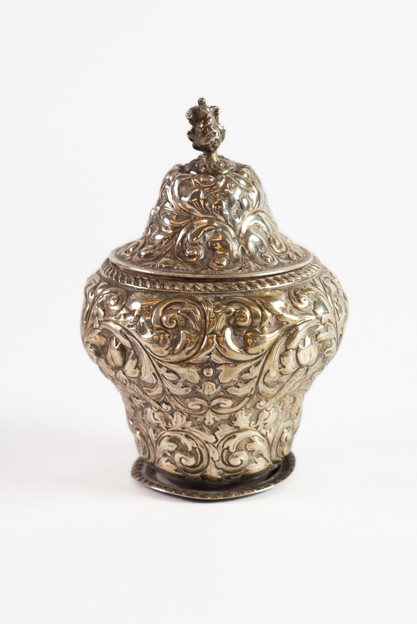 VICTORIAN EMBOSSED SILVER TEA CADDY AND COVER, of footed baluster form with foliate scroll cast knop