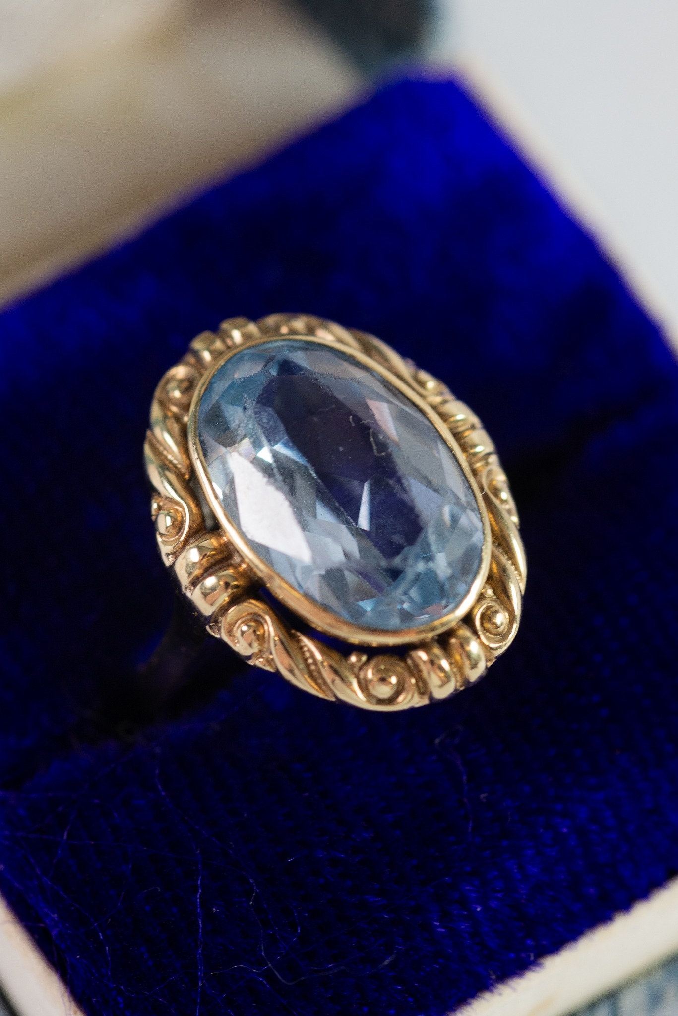 GOLD COLOUR METAL (no carat mark) PROBABLY AQUAMARINE COLLET SET DRESS RING within a scrollwork
