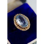 GOLD COLOUR METAL (no carat mark) PROBABLY AQUAMARINE COLLET SET DRESS RING within a scrollwork