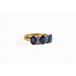 18ct GOLD BROAD RING set with three oval sapphires and two pairs of tiny white sapphires, 7.3gms,