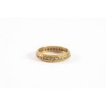 18ct YELLOW AND WHITE GOLD FACETED ETERNITY RING set with tiny white stones, 4.8gms,