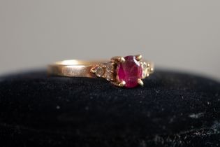 9ct GOLD RING set with a centre oval red stone and a trio of tiny diamonds to each shoulder, 2.2gms,