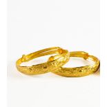 PAIR OF CHINESE GOLD SLIDE-EXPANDING SPRUNG BANGLES, each repousse with a sun flanked by a pheonix