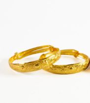 PAIR OF CHINESE GOLD SLIDE-EXPANDING SPRUNG BANGLES, each repousse with a sun flanked by a pheonix
