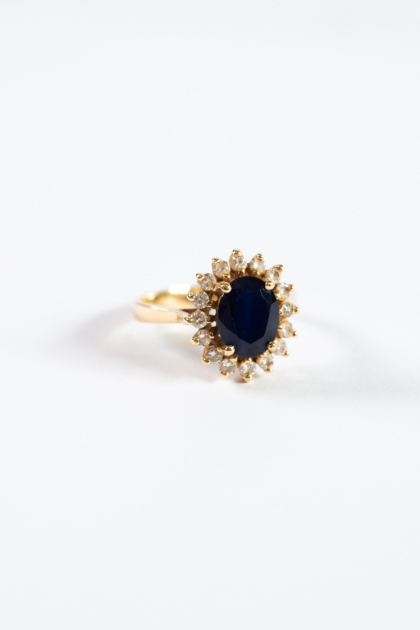 GOLD COLOURED METAL, SAPPHIRE AND DIAMOND OVAL CLUSTER RING, set with a surround of 16 small