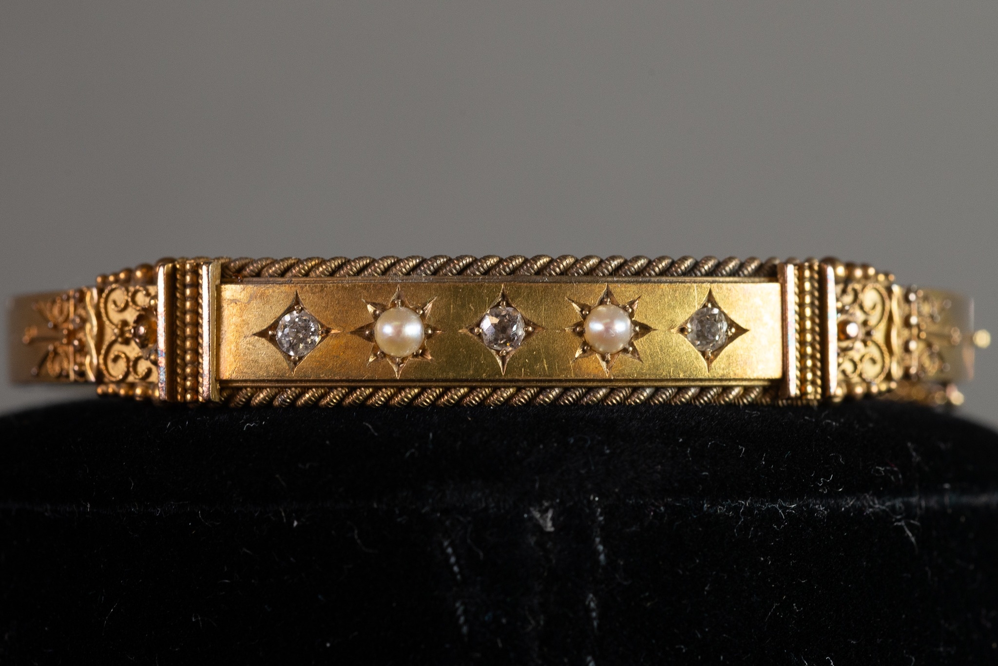 VICTORIAN 15ct GOLD HOLLOW BANGLE, hinge opening, the top half filigree decorated with a plain panel