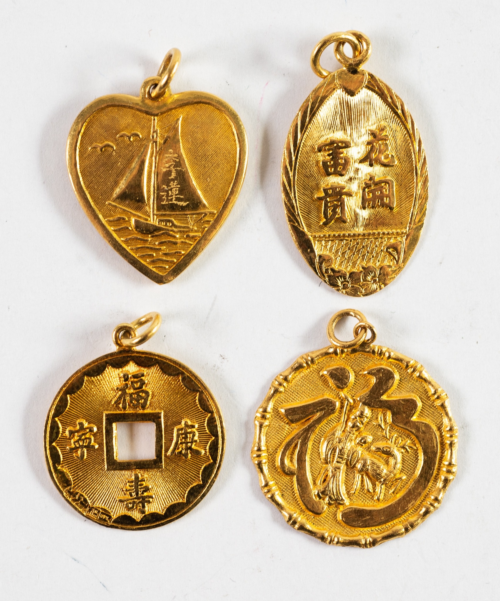 FOUR CHINESE GOLD EMBOSSED PENDANTS, one in the form of a coin with centre square hole; one heart