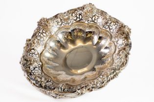 VICTORIAN EMBOSSED AND PIERCED SILVER SWING HANDLED CAKE BASKET, of circular footed form with floral