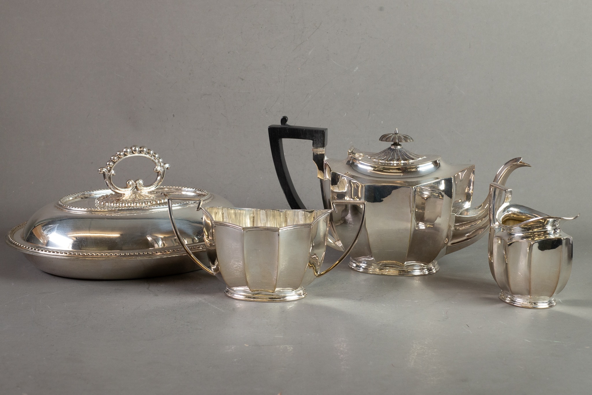 THREE PIECE ELECTROPLATED TEASET, of oval panelled form with black angular scroll handles and oval