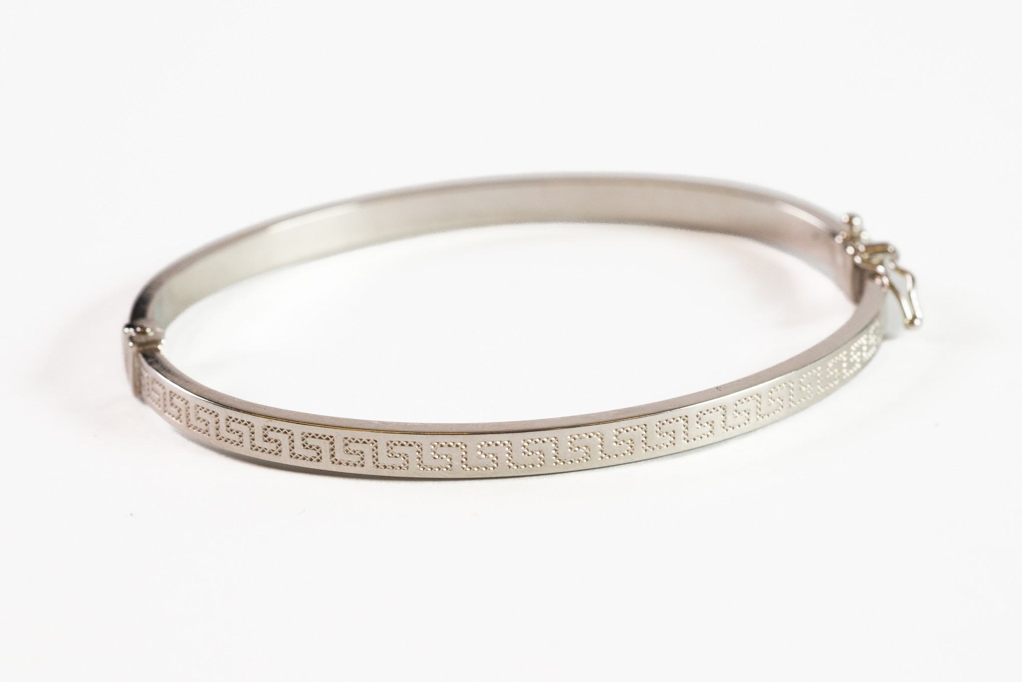 18ct WHITE GOLD NARROW HINGE-OPENING BANGLE, with engraved Greek key decoration, 2 5/8in (6.7cm)