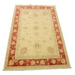 INDIAN RUG with an all over beige formal floral pattern with red highlights, the principal border