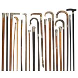 A collection of Victorian and later walking sticks and canes, mostly with silver tops and collars