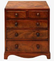 An early 19th century figured mahogany miniature chest of drawers