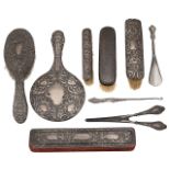 An Edwardian embossed silver hand mirror, clothes brushes and other items