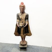 A Thai carved and painted wooden figure of a standing Deity, H. 117cm.