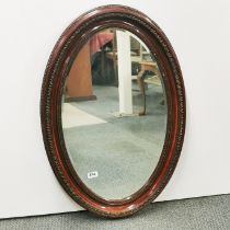 A carved and re-finished oval mirror, 80 x 55cm.